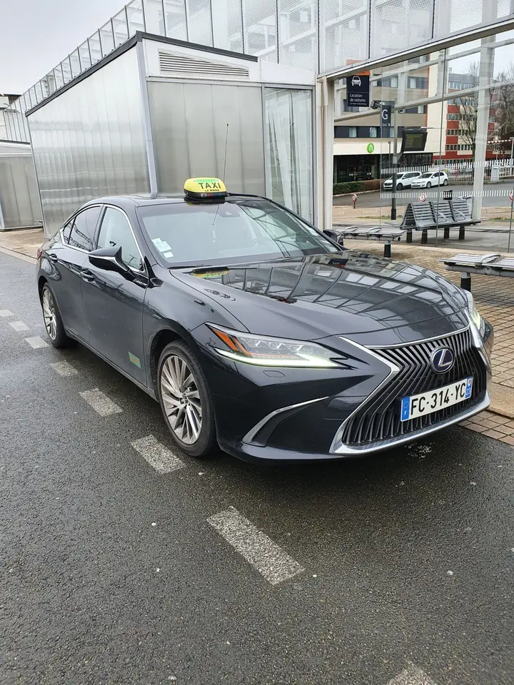 La berline hybride noire de Taxi Bouti vue de face, enseigne taxi allumée, sur une station de taxis